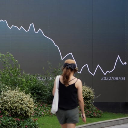 A pedestrian walks past a giant display showing a stock graph in Shanghai on August 3, 2022. Photo: Reuters