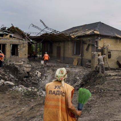 An elderly worker with a broom inspects a crater caused by a rocket strike on a house in Kramatorsk, Donetsk region, eastern Ukraine. Photo: AP