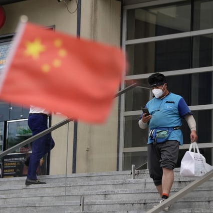 A delivery man walks near a Chinese flag in Beijing on Monday. Photo: AP Photo