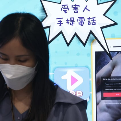 A woman wearing a face mask stands in front of a display that features warning messages about cybercrime scams, including blackmail and online extortion, with illustrations of smartphones and scam-related warnings.