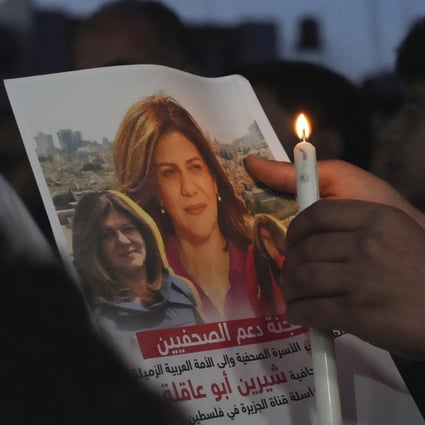 A Palestinian holds a picture of slain Palestinian-American Al Jazeera journalist Shireen Abu Akleh, during a candlelight event to condemn her killing. File photo: AP