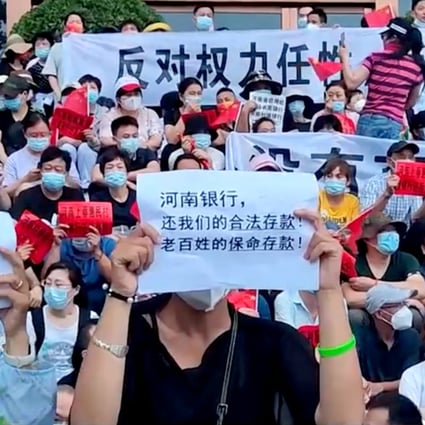 Bank customers stage a protest in Zhengzhou, Henan province, on July 10, after their funds were frozen by local banks. The sign in the foreground reads: “Henan Bank, return to us our legal deposits! The people’s life-saving deposits!” Photo: Reuters