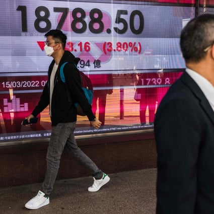 A man walks past a display showing the Hang Seng Index in March 2022. Photo: AFP