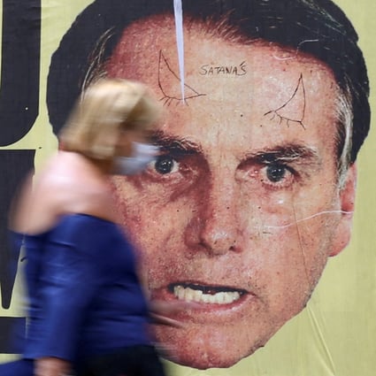 People walk past a poster depicting Brazil’s President Jair Bolsonaro with the phrase “Bolsonaro in jail” in Sao Paulo in January. Photo: Reuters