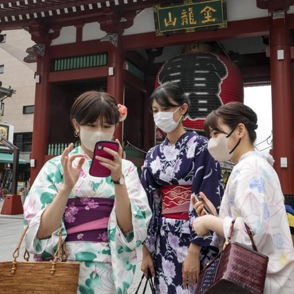 Tourists clad in traditional Japanese dress take pictures in front of the Kaminarimon gate of Sensoji temple in Asakusa, downtown Tokyo, last week. Photo: EPA-EFE