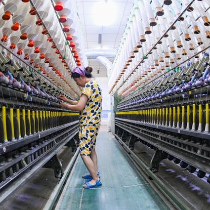 A worker checks a machine at the workshop of a textile enterprise in Qingzhou Economic Development Zone in east China’s Shandong province, on July 27, 2022. Photo: Future Publishing via Getty Images