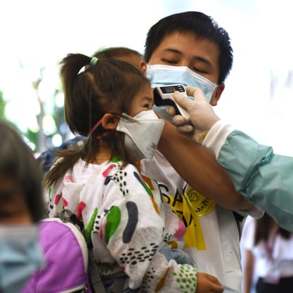A worker takes the body temperature of a child in Singapore. File photo: Xinhua 