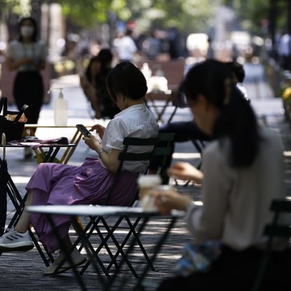 Women sit in the shade in the Marunouchi district of Tokyo, on July 1. In Japan, amid official encouragement, companies are beginning to embrace a four-day working week. Photo: Bloomberg