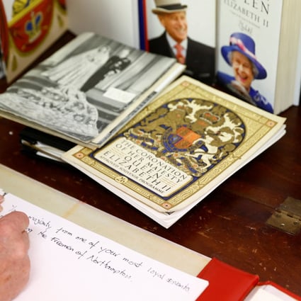 A person writes condolences on the papers that will make a book of remembrance, following the death of Britain’s Queen Elizabeth. Photo: Reuters