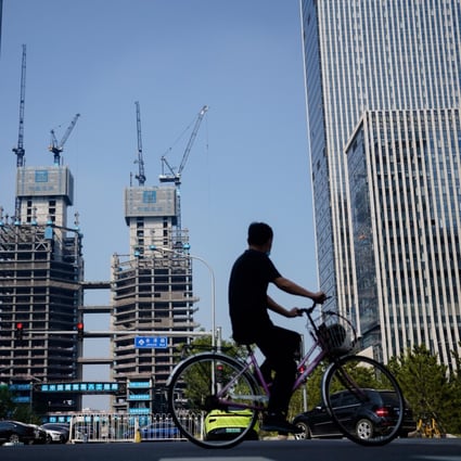 A man rides a bike past residential buildings under construction in Beijing on September 15. Property demand has slumped alongside the rate of marriages as more men are unable to take on the crippling financial responsibility of providing a matrimonial home. Photo: EPA-EFE