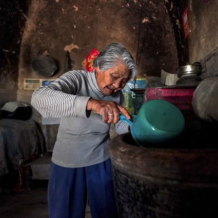 An elderly woman scoops water from a pail at her rural village home in Yicheng county in Shanxi province on July 3, 2019. Photo: Xinhua