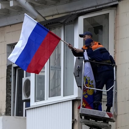 Workers hang Russian flags outside an apartment building in Luhansk, eastern Ukraine on Tuesday. Photo: AP