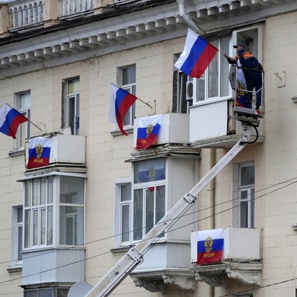 Workers hang Russian flags at an apartment building in Luhansk. Photo: AP