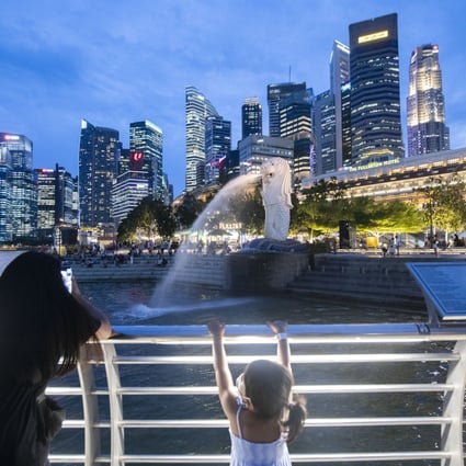 Tourists take pictures of the iconic Merlion statue in Singapore this month. The city state’s population grew this year, as Hong Kong’s continued to decline. Photo: Xinhua