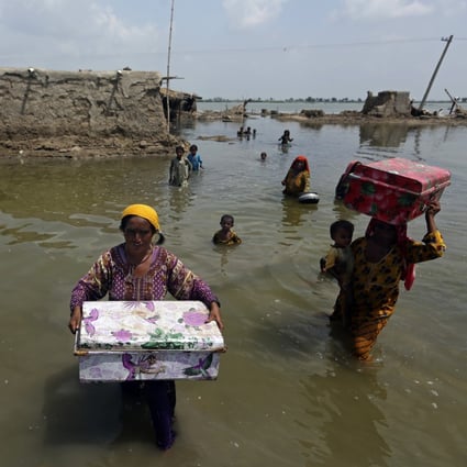 Women carry belongings salvaged from their flooded home following monsoon rains in the Qambar Shahdadkot district of Sindh province, in Pakistan, on September 6. Photo: AP