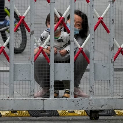 A woman and a child look out through gaps in the barriers at a closed residential area during a Covid-19 lockdown, in Shanghai, on May 10. Photo: Reuters
