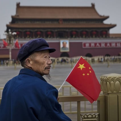 An elderly Chinese man holds a flag as he stands in Tiananmen Square on the 65th National Day on October 1, 2014 in Beijing. Photo: Getty Images