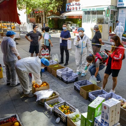 Residents stand behind a cordon at a fruit stall in the Tianshan district of Urumqi in Xinjiang on September 5. Photo: cnsphoto via Reuters