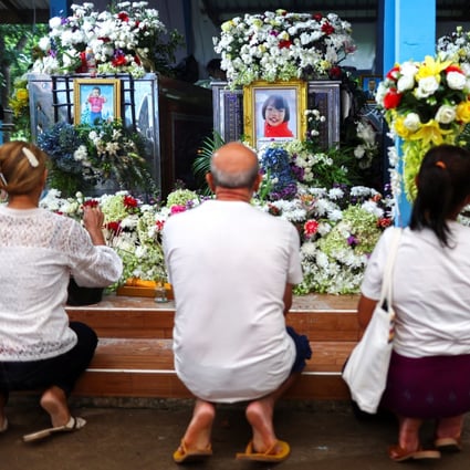 Families in Thailand pray following a mass shooting last week which claimed 36 lives, including children. Photo: Reuters
