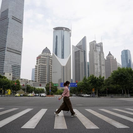 A pedestrian crosses a road in the Lujiazui financial district in Shanghai. Photo: Reuters