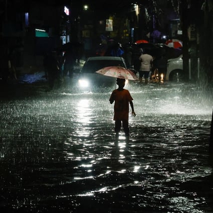 A boy in Dhaka wades through a street flooded by continuous rain before Cyclone Sitrang made landfall on Monday. Photo: Reuters