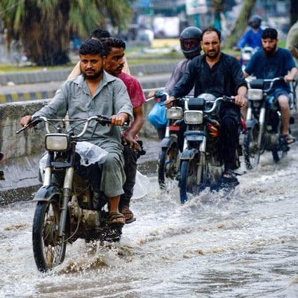 Motorcyclists make their way through a flooded street after heavy rains in Karachi on September 12. In climate-hit Pakistan, for example, the AIIB is part of a project to link up the megacity through a network of hybrid buses, partly run on biogas, to make commuting faster and safer. Photo: AFP