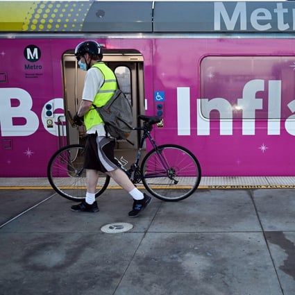 A cyclist pushes a bicycle past a Metro green line light rail train wrapped with a “Beat Inflation” advertisement for the 99 Cents Only Stores, in Redondo Beach, California. Photo: AFP