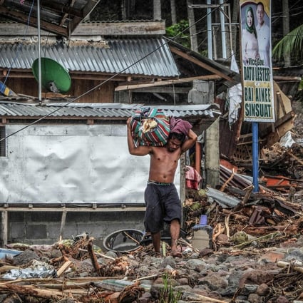 A resident carrying belongings walks amongst debris from landslide in the landslide-hit village of Kusiong in the southern Philippines’ Maguindanao province on Saturday. Photo: AFP