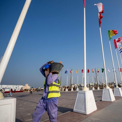 A worker carries a bucket of building materials past the World Cup stadium in Doha. Photo: AFP