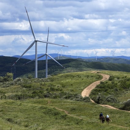Tourists ride horses near wind turbines on the grassland in Zhangbei county, Hebei province, on August 15. China, currently the top emitter of greenhouse gases in the world, aims to reach net zero by 2060, requiring significant slashing of emissions. Photo: AP