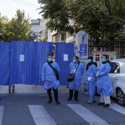 Officials in protective aprons stand outside the boarded-up gate of a residential compound placed under lockdown on Tuesday as Covid-19 outbreaks continue in Beijing. Photo: Reuters