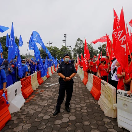 A policeman stands guard between rival groups of Barisan Nasional (left) and Pakatan Harapan supporters outside a nomination centre in Pahang on nomination day. Photo: Reuters