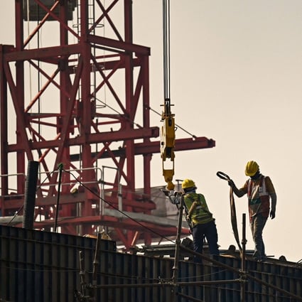 Workers stand atop scaffolding at an under-construction flyover site in New Delhi on November 21. Photo: AFP