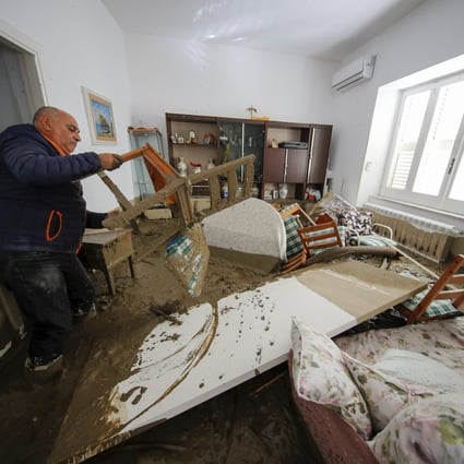 A man walks among mud and debris in his home on Sunday after heavy rain triggered landslides that killed at least 2 on the Italian island of Ischia. Photo: AP