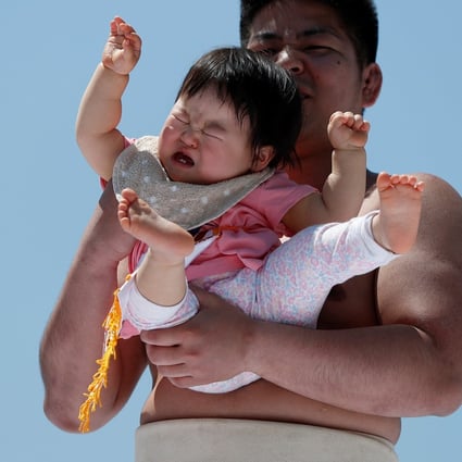 An amateur sumo wrestler holds a baby during a baby crying contest at a temple in Tokyo in 2018. The annual number of births in Japan is projected to fall to 740,000 by 2040. Photo: Reuters
