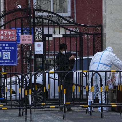 A man wearing a face mask asks a worker in a protective suit to pick up his groceries in a neighbourhood under lockdown in Beijing on November 27. Photo: AP 