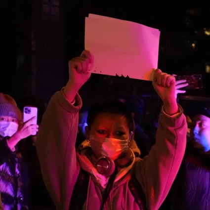 Protesters hold up blank sheets of paper and chant slogans as they march in Beijing on Sunday. Photo: AP