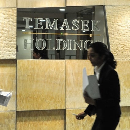 Office workers walk past Singapore state-linked investment firm Temasek Holdings sign. File photo: AFP