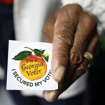 A poll worker in the US holds a Georgia voter sticker. Photo: TNS
