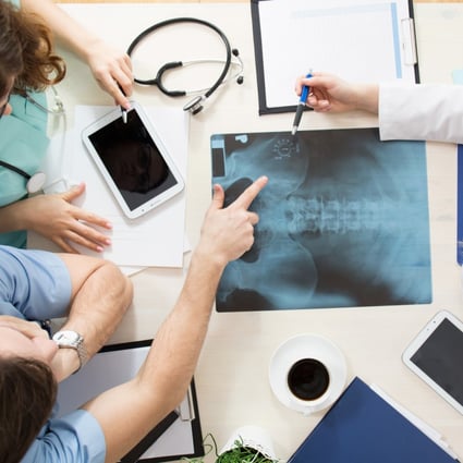 Doctors sitting around the table and interpreting x-ray image. Photo: Shutterstock/File