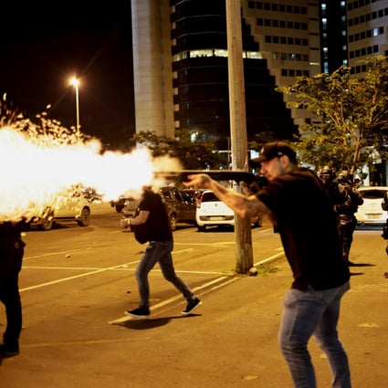 A police officer fires a gun as supporters of Brazil’s outgoing President Jair Bolsonaro protest after a supreme court justice ordered that an indigenous leader be arrested for alleged anti-democratic acts. Photo: Reuters