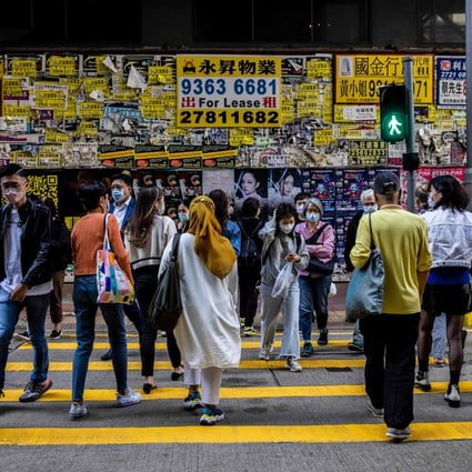 Pedestrians cross a road in front of a vacant shop in Hong Kong on December 9, 2022. Photo: AFP