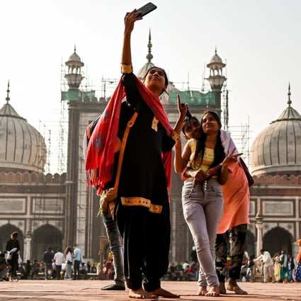 People take selfies with their phones as they visit the Jama Masjid of Delhi, one of the largest mosques in India, on November 26. India’s young population is attractive to businesses looking for new markets. Photo: AFP 