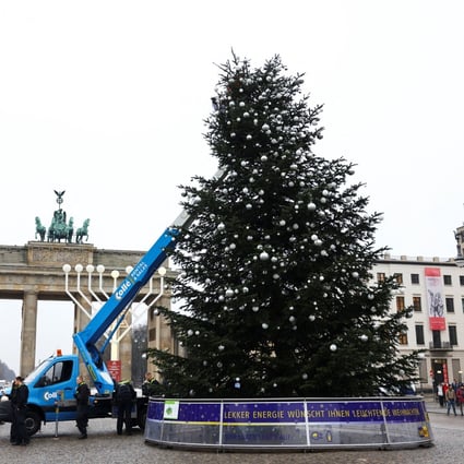Last Generation activists cut the top off a Christmas tree at Brandenburg Gate, in Berlin, Germany. Photo: Reuters