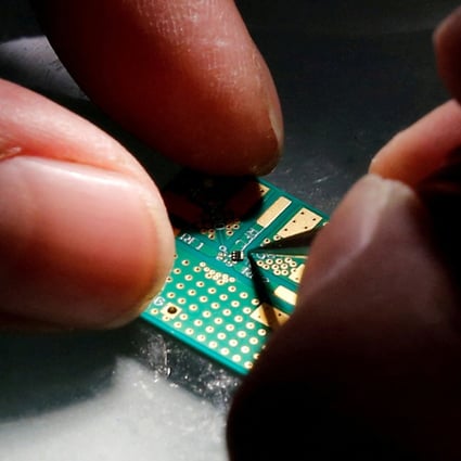 A researcher plants a semiconductor on an interface board at Tsinghua Unigroup’s research centre in Beijing. Photo: Reuters