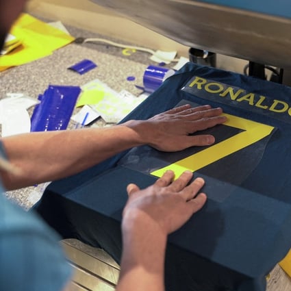 A staff member heat presses an Al Nassr jersey with Cristiano Ronaldo’s surname on the back, in Riyadh. Photo: Reuters