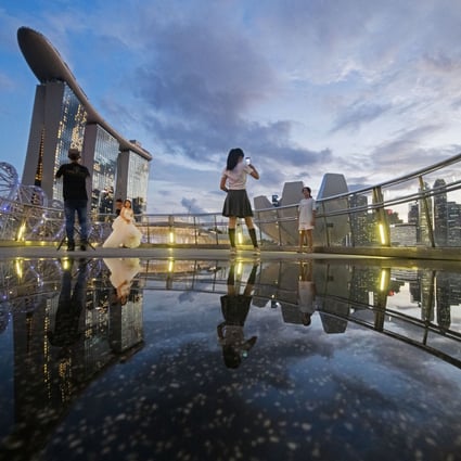 People take photos at Singapore’s Marina Bay last month. The city state’s economic performance is often seen as a useful barometer because of its reliance on trade with the rest of the world. Photo: Xinhua