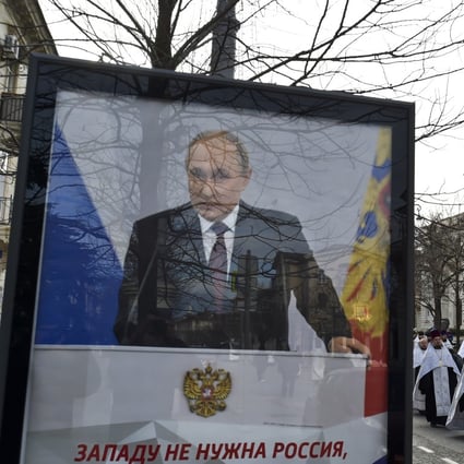 A poster of President Vladimir Putin with the words “The West does not need Russia” in Sevastopol, Crimea, as Russian Orthodox priests participate in a procession celebrating Orthodox Christmas. Photo: AP 
