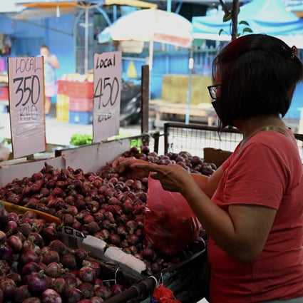 A woman buys onions at a market in Manila on Wednesday amid soaring prices for the food staple. Photo: AFP