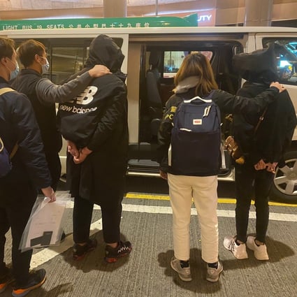 Two hooded and handcuffed suspects are being escorted into an unmarked police vehicle after the pair were arrested in a Mong Kok hotel room on Monday. Photo: Handout